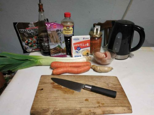 Tous les ingrédients pour faire des nouilles soba en bouillon et devant, une planche à découper et un grand couteau