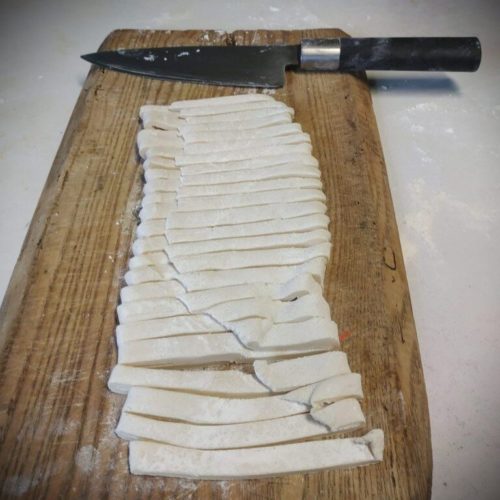Une planche à découper et des lanières de pâte à udon maison