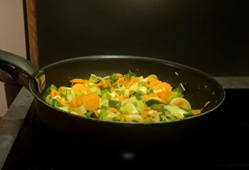 Des légumes dans un wok pour faire une recette de yaki udon