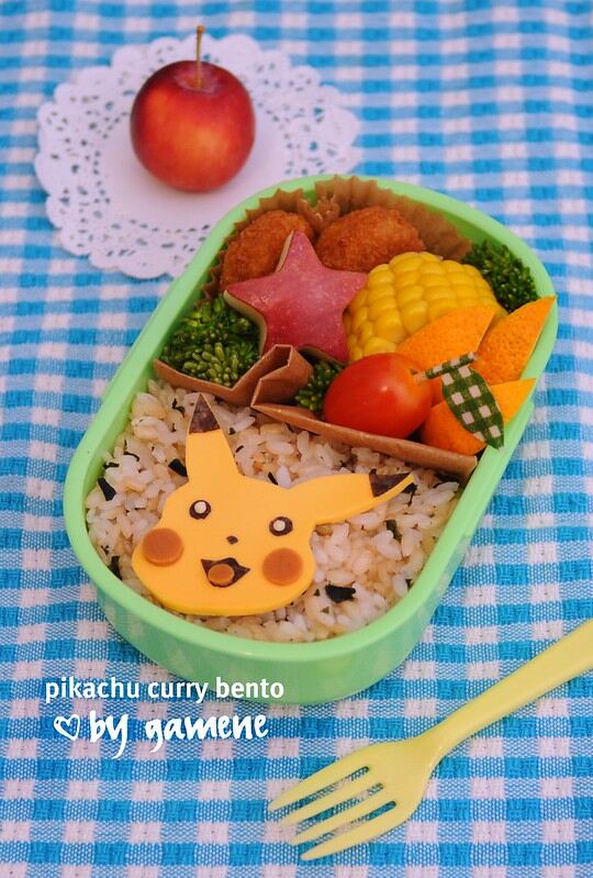 Une boite à repas japonais ou bento conçu pour les enfants avec du riz, des légumes et un assemblage d’aliment représentant Pikachu