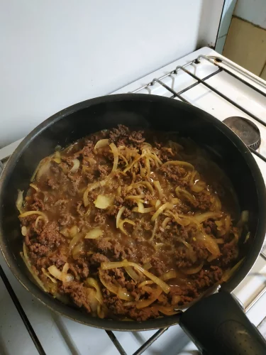 Dans une poêle, faire revenir les oignons, la viande de boeuf le bouillon à base de dashi. C'est une étape clé de la recette du gyudon